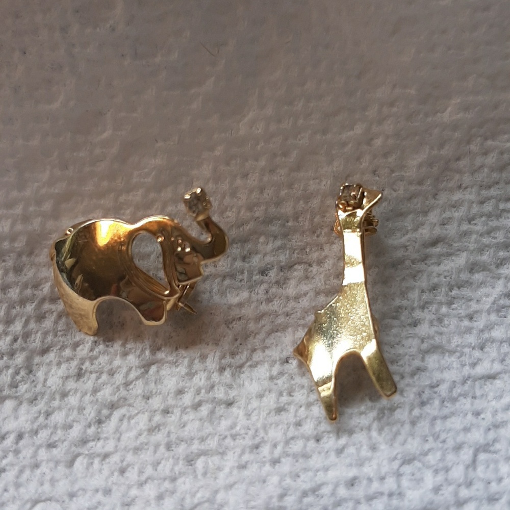 Two gold toned pins one giraffe, one elephant